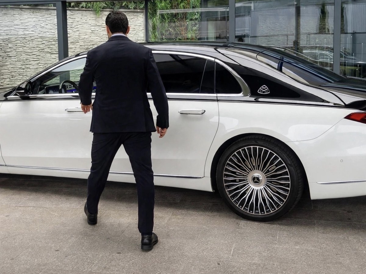 Chauffeur Velour en costume ouvrant la portière arrière d'une Mercedes Classe S